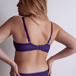 Model wearing 'Illusion Fauve' Half Cup Bra in violet, by Aubade (back view).